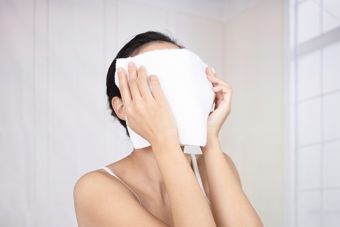 蒸しタオルで顔を覆う女性
